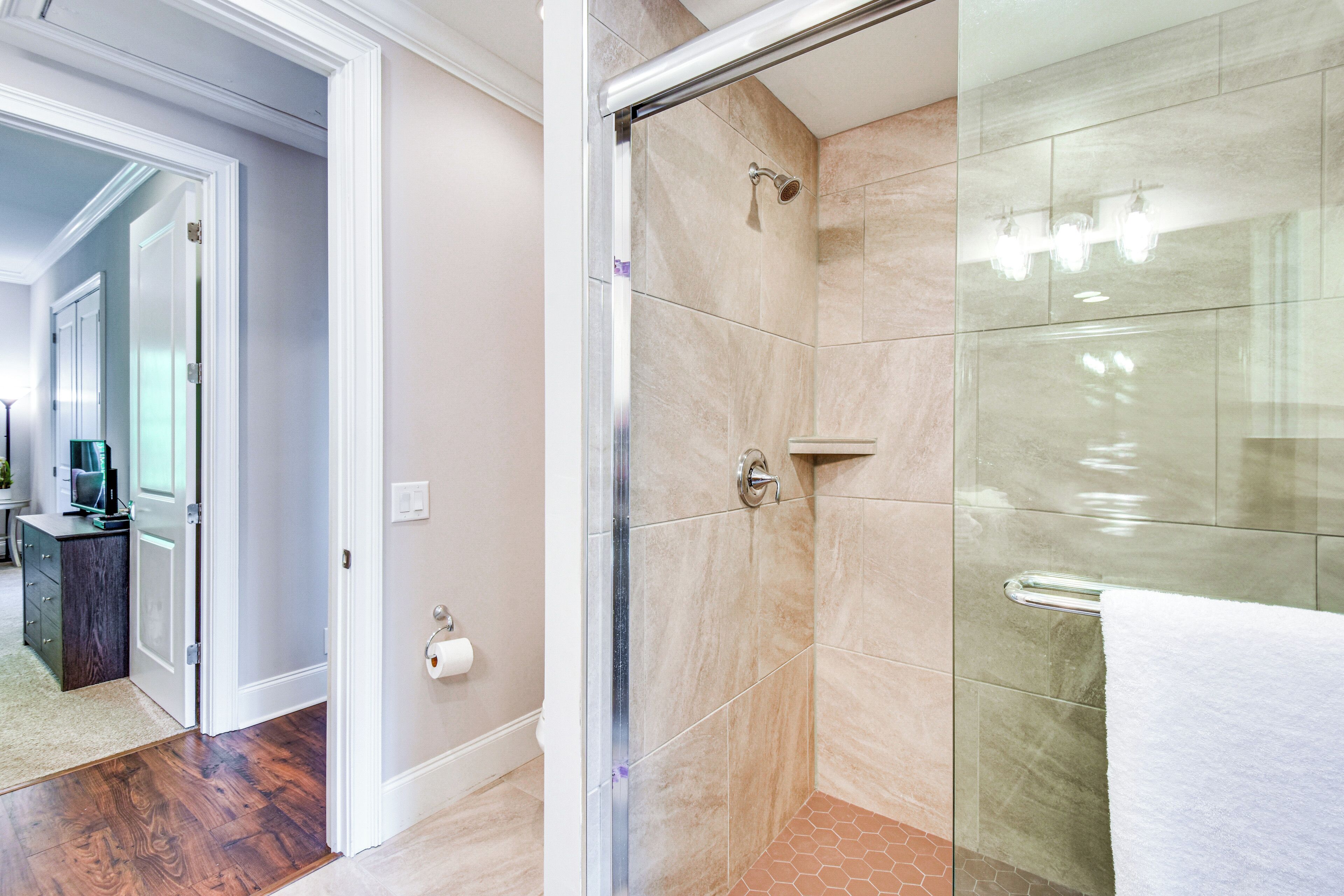 Un baño moderno con cabina de ducha de vidrio, una toalla blanca y un dispensador de papel higiénico.