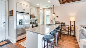 A modern kitchen with a central island, stainless steel appliances, and bar stools. - Community Perks: Mountain-view Condo in Toccoa! (Toccoa)