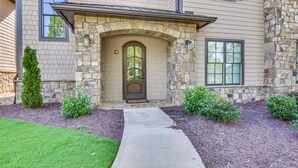 A two-story house with a stone facade, a front door with a glass panel, and a pathway leading to the entrance. - Community Perks: Mountain-view Condo in Toccoa! (Toccoa)