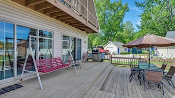 A wooden deck with outdoor furniture, a swing, and a barbecue area.