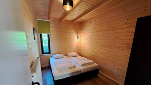 A small, cozy room with wooden walls and a single bed.