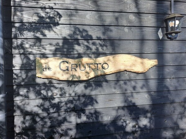 A wooden sign with the text 'de GRUTTO' on a dark wooden wall.