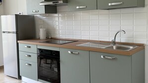 A modern kitchen with light green cabinets, a stainless steel sink, and a built-in dishwasher.