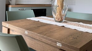 A dining table with a clear glass vase containing dried plants, set on a wooden table with a lace table runner.