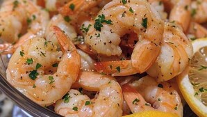 Prato de camarões cozidos, adornado com ervas e rodelas de limão.