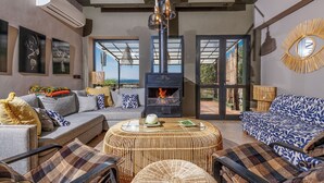 Una sala de estar moderna con chimenea, asientos cómodos y ventanas grandes que ofrecen una vista.