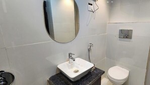 A modern bathroom with a white sink, mirror, and toilet. - Aryston Hotel Udaipur (Udaipur)