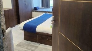 A hotel room with a bed, a window with curtains, a wardrobe, and a door marked with the number 105. - Aryston Hotel Udaipur (Udaipur)