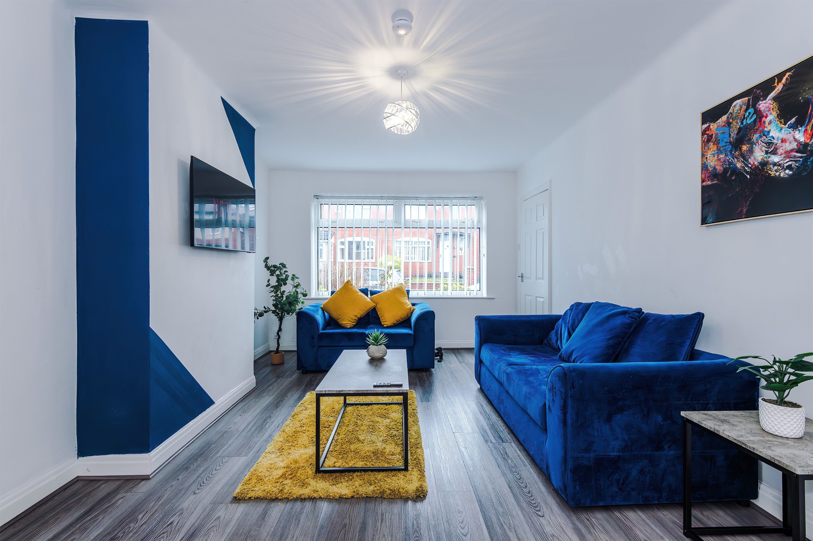 Ein Wohnzimmer mit einem blauen Sofa, einem Couchtisch und einem gelben Teppich.