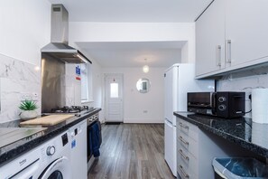A compact kitchen with a washing machine, a microwave, and a toaster.