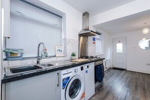 A modern kitchen with a built-in washing machine, stainless steel sink, and a large window.