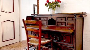 Un escritorio de madera con cajones, una silla y un espejo.