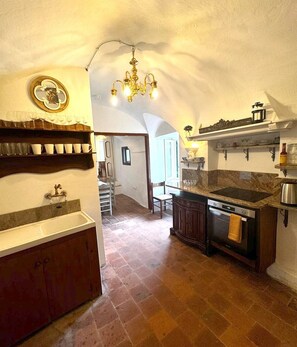 Una cocina con encimera de mármol, horno empotrado y lámpara colgante.