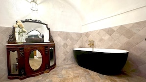 Un baño con una bañera independiente, un tocador con espejo y un aplique de pared.