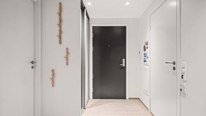 A hallway with white walls, a wooden floor, and a dark door at the end. - City Apartment | Modern & Spacious (Bergen)