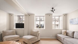 Ein modernes Wohnzimmer mit zwei Sofas, einem kleinen runden Tisch und einem an der Wand befestigten Fernseher.