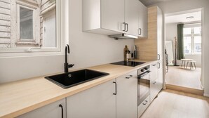 A modern kitchen with a black sink, white cabinets, and a wooden countertop. - City Apartment I Cozy with Perfect Location (Bergen)