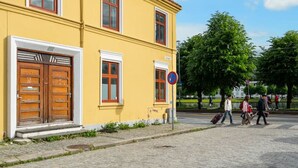 A yellow building with a red-tiled roof, a wooden door, and a window with a white frame. - City Apartment I Cozy with Perfect Location (Bergen)