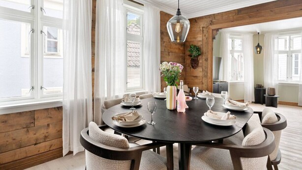 Un coin repas avec une table ronde dressée pour six personnes, entourée de chaises rembourrées.