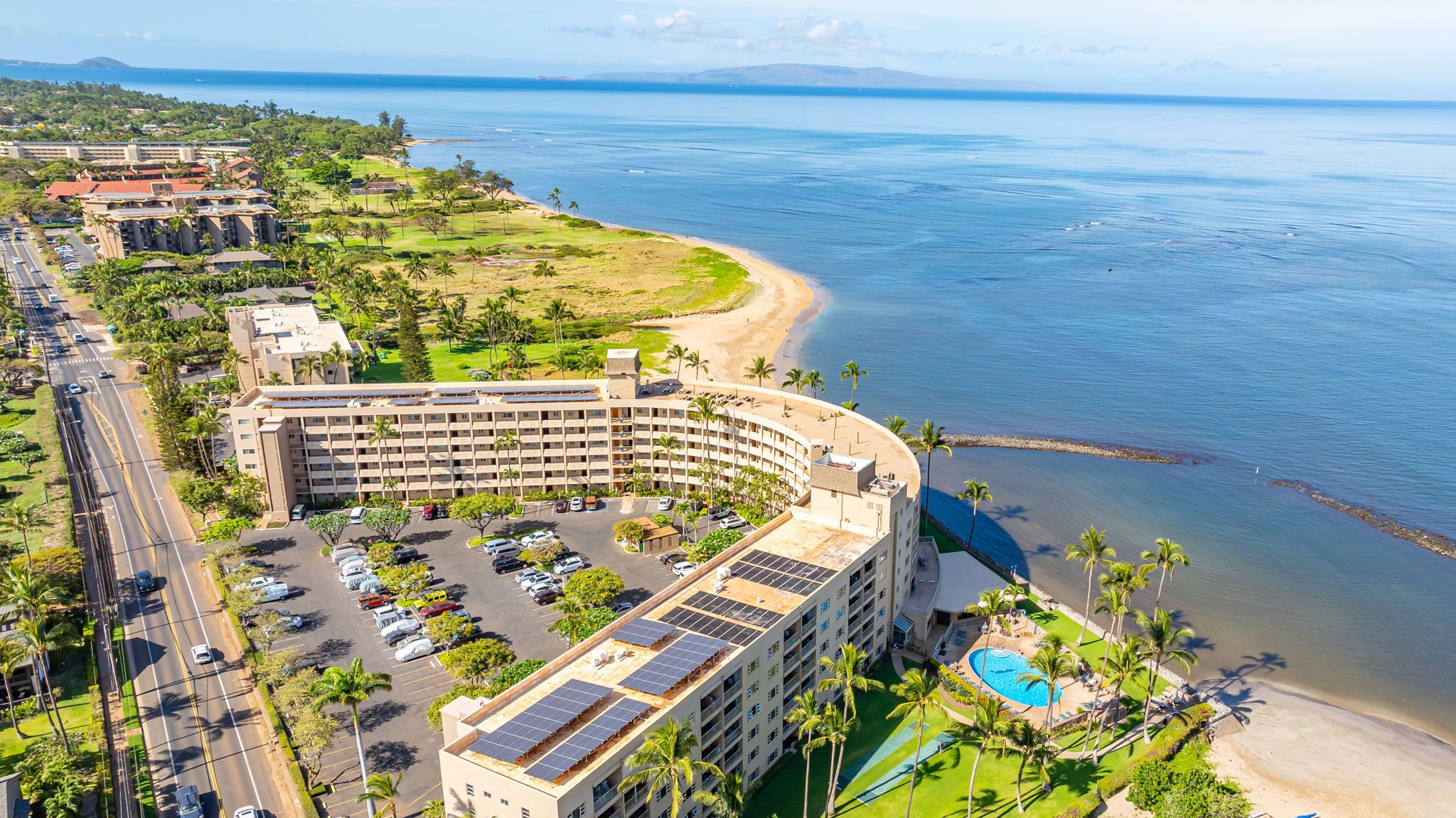 A hotel with a pool, a beach, and a view of the ocean.