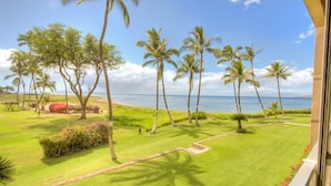 A well-maintained lawn with palm trees and a view of the ocean.