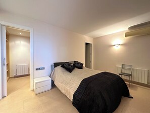 A bedroom with a bed, bedside table, chair, and a radiator. - Architect-designed home with exceptional panoramic ocean views and an infinity pool (Castell-Platja d'Aro)