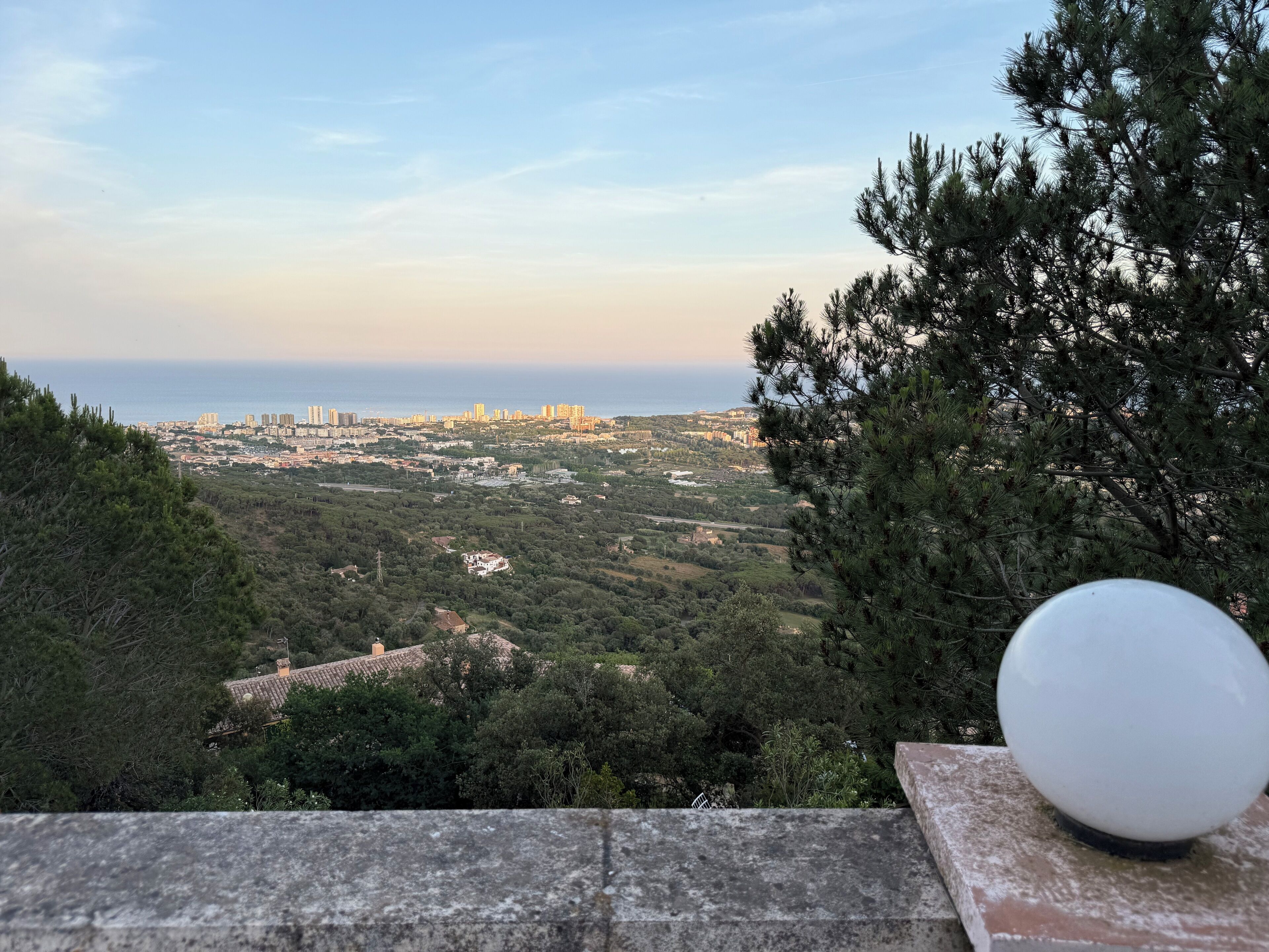 A view from a balcony overlooking a coastal cityscape with buildings and greenery.