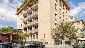Un immeuble à plusieurs étages doté de balcons, d’un espace de stationnement et donnant sur la rue.
