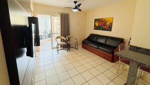 A living room with a black leather sofa, two chairs, a dining table, a ceiling fan, and a painting on the wall. - Eldorado Park (Caldas Novas)