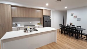 Una cocina moderna con armarios de madera, encimera blanca y un lavamanos integrado.