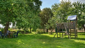 A grassy outdoor area with a wooden play structure and a table with chairs. - Apartment 'Uschi' with Shared Garden and Wi-Fi (Warrenzin)