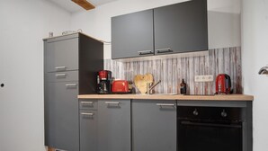 A compact kitchen with grey cabinets, a wooden countertop, a red toaster, and a built-in oven. - Apartment 'Uschi' with Shared Garden and Wi-Fi (Warrenzin)