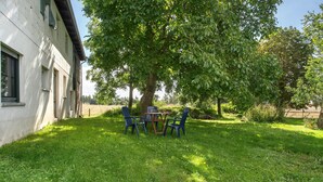 A grassy outdoor area with a table and chairs under a tree, adjacent to a building with windows. - Apartment 'Uschi' with Shared Garden and Wi-Fi (Warrenzin)