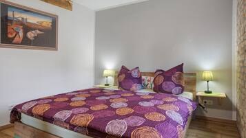 Un dormitorio con cama, dos lámparas de noche, un cuadro en la pared y suelo de madera.