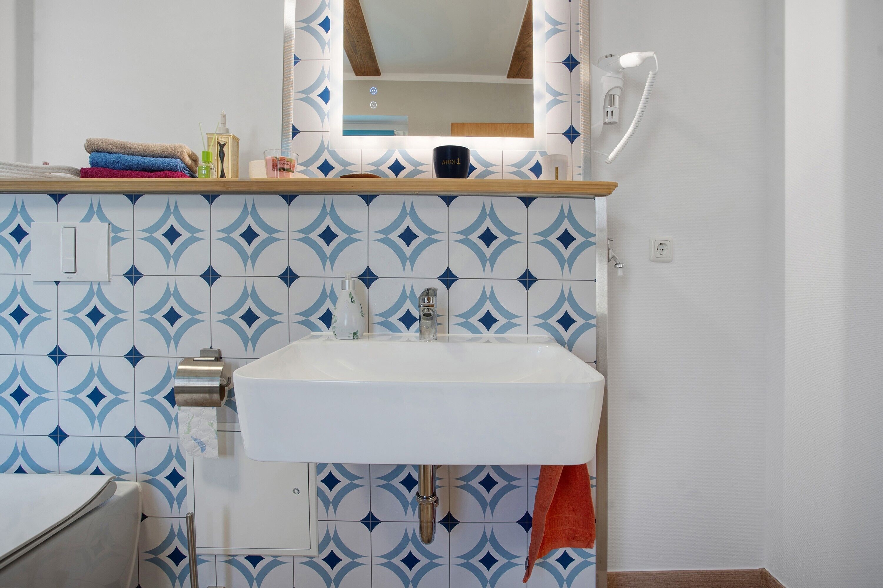 A bathroom with a sink, mirror, and patterned tiles.