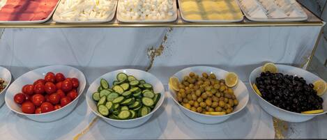 Buffet amb diverses opcions gastronòmiques, com ara tomàquets, cogombres, olives i formatge.