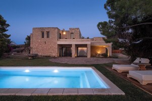 Una piscina al aire libre, sombrillas, sillones reclinables de piscina