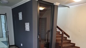 A spacious room with a tiled floor, a dark accent wall, and a wooden staircase. - Luxurious & Spacious
Swakopmund Accommodation (Swakopmund)