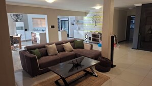 A modern living room with a brown sofa, a coffee table, and a kitchen in the background. - Luxurious & Spacious
Swakopmund Accommodation (Swakopmund)