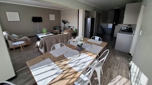 A modern living room with a dining area, a sofa, a small table with a plant, and a television on the wall. - Luxurious & Spacious
Swakopmund Accommodation (Swakopmund)