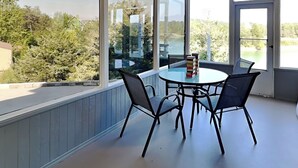 Un espace de restauration extérieur moderne, doté d’une table et de chaises en verre, offrant une vue sur un paysage pittoresque.