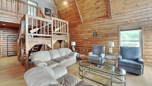 Un vaste espace de vie avec une chambre en mezzanine, des murs en bois et une grande fenêtre.