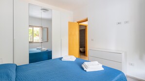 A bedroom with a bed, a wardrobe, a bathroom, and a mirror. - La Casa di Samu - White Apartment (Arbatax)