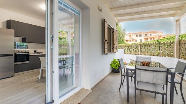 A modern kitchen with a sliding glass door leading to a balcony with outdoor seating. - La Casa di Samu - White Apartment (Arbatax)