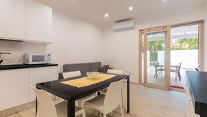 Une cuisine moderne avec des meubles blancs, un four à micro-ondes et un coin repas comprenant une table noire et des chaises blanches.