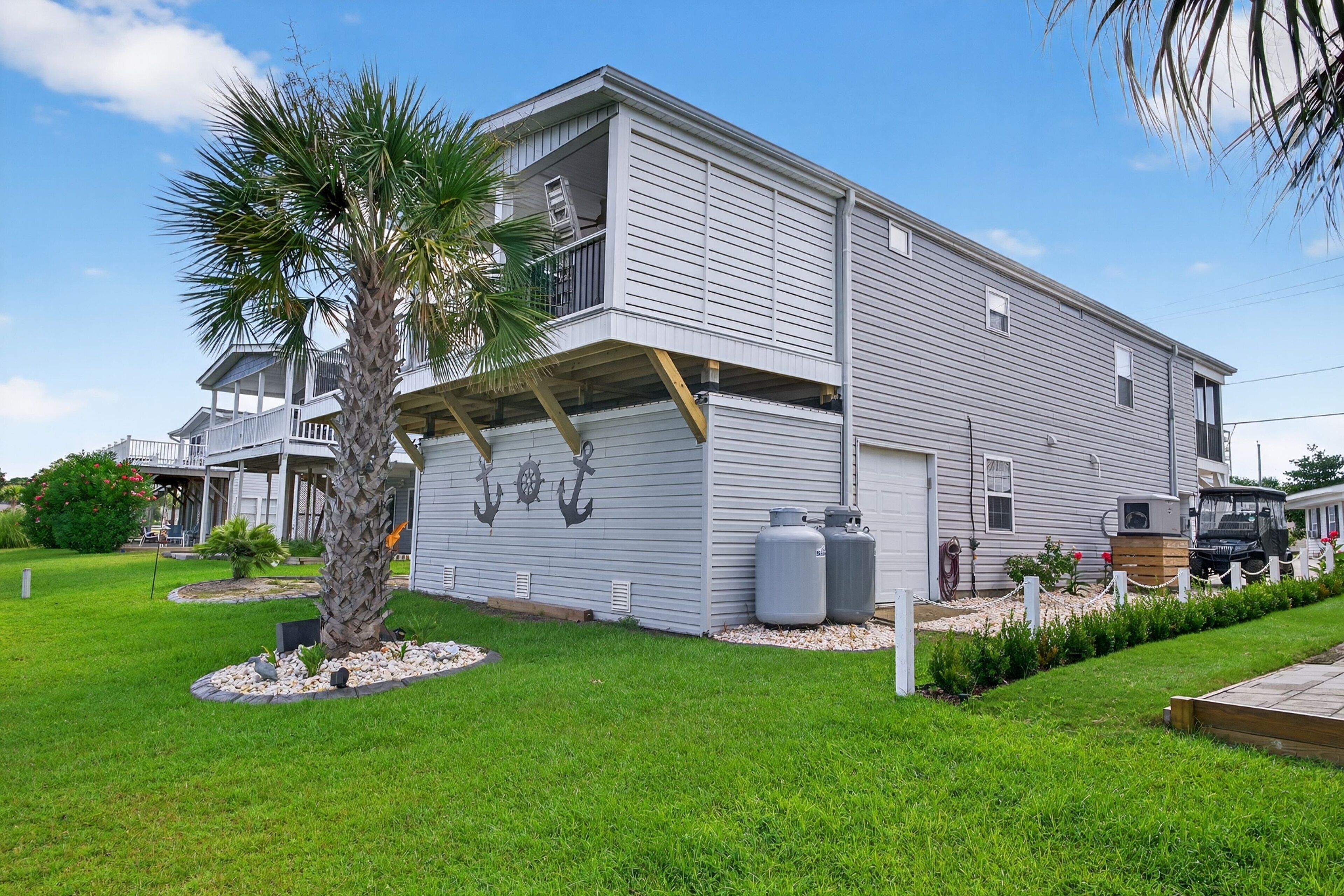 A two-story house with a garage, a palm tree, and a well-maintained lawn.