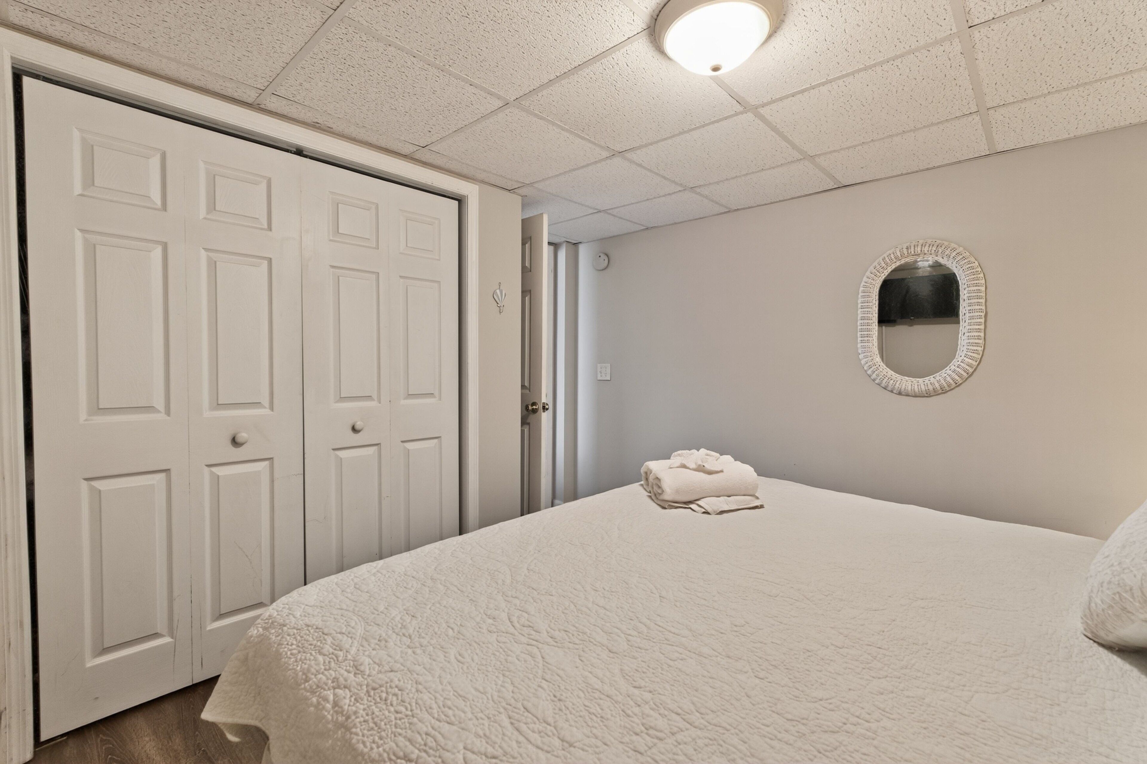 A bedroom with a large bed, a white door, and a mirror on the wall.