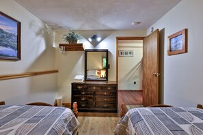 Un dormitorio con dos camas, un aparador, un espejo y una puerta que da a otra habitación.
