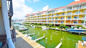 A waterfront hotel with multiple balconies, a dock, and a marina with boats. - Aronimink 1b 2 Bedroom Condo (Ocean City)