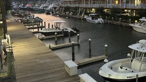 Un port de plaisance avec des bateaux amarrés, une passerelle en bois et, au fond, un bâtiment doté de balcons.